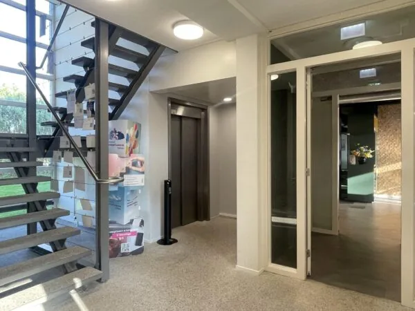 Ingangshal van een kantoorpand aan de Jan Leentvaarlaan met een trap, lift en glazen deur.